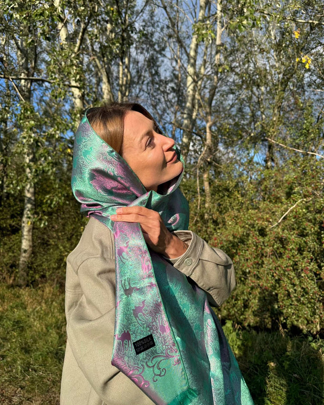 kobieta w zielono fioletowym szalu jedwabnym z motywem karawany wielbłądów na tle natury