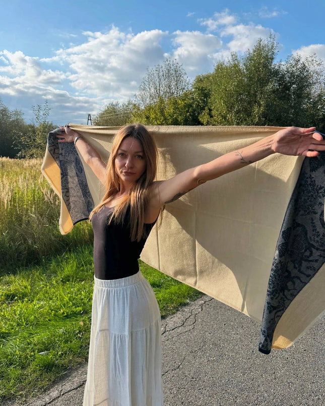 kobieta trzyma luksusowy szal kaszmirowy biały z niebieskimi wielbłądami na tle natury